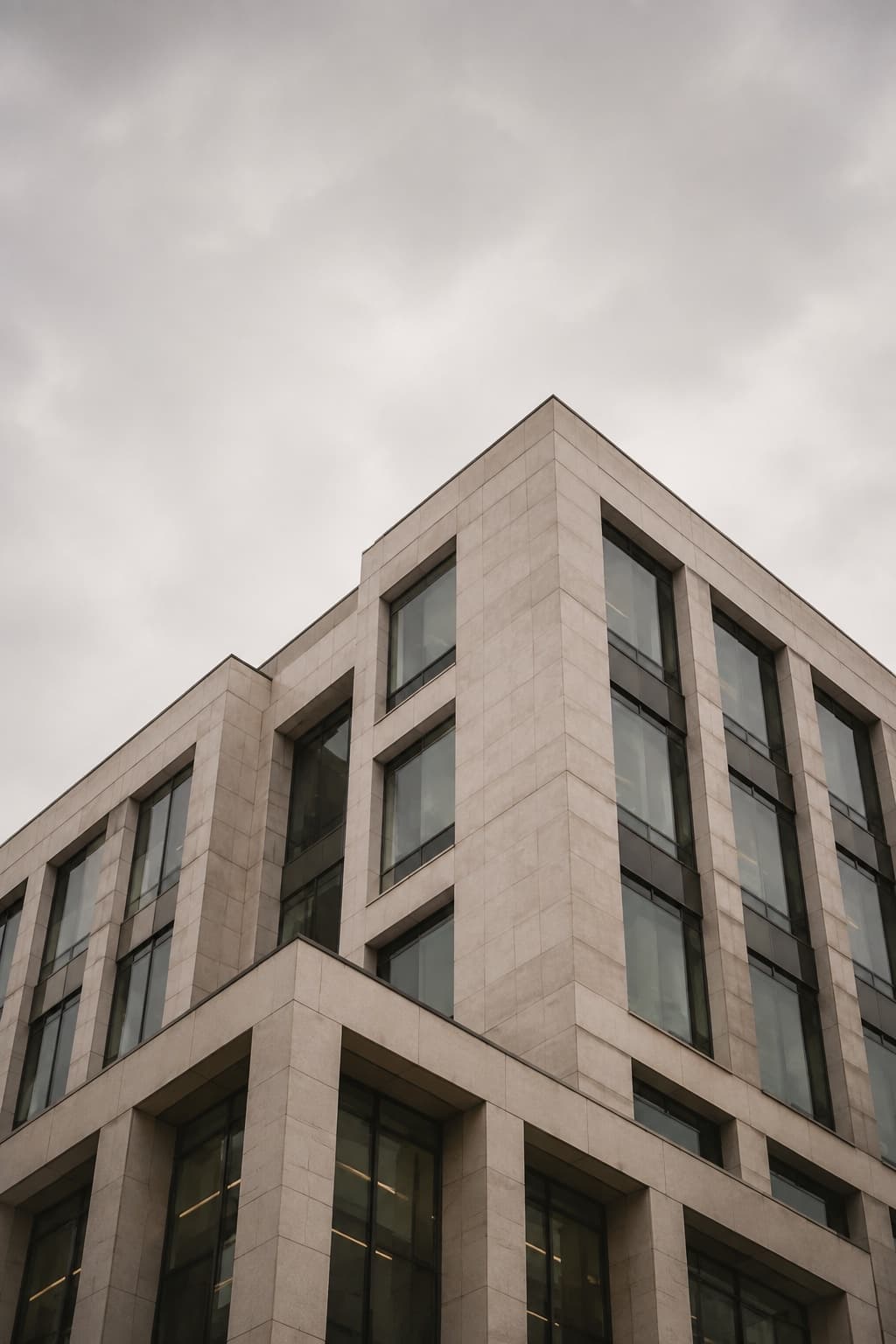 Modern stone and glass office building beneath an overcast sky